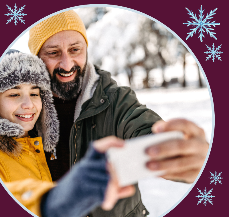 Man and child dressed for winter and holding a phone